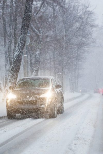 Cars Moving On Slippery Snowy Road At City Street During Heavy S