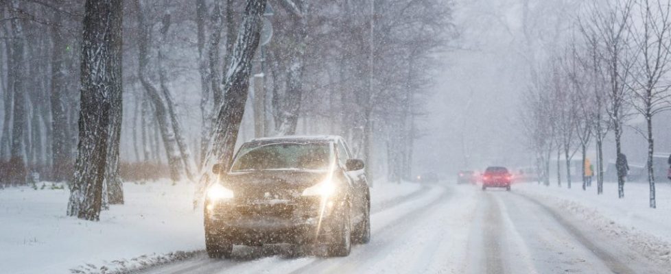 Cars Moving On Slippery Snowy Road At City Street During Heavy S